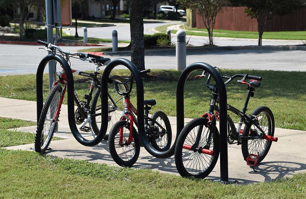 Wave bike rack holding multiple bicycles on a sidewalk demonstrating proper parking and spacing for secure urban bike storage
